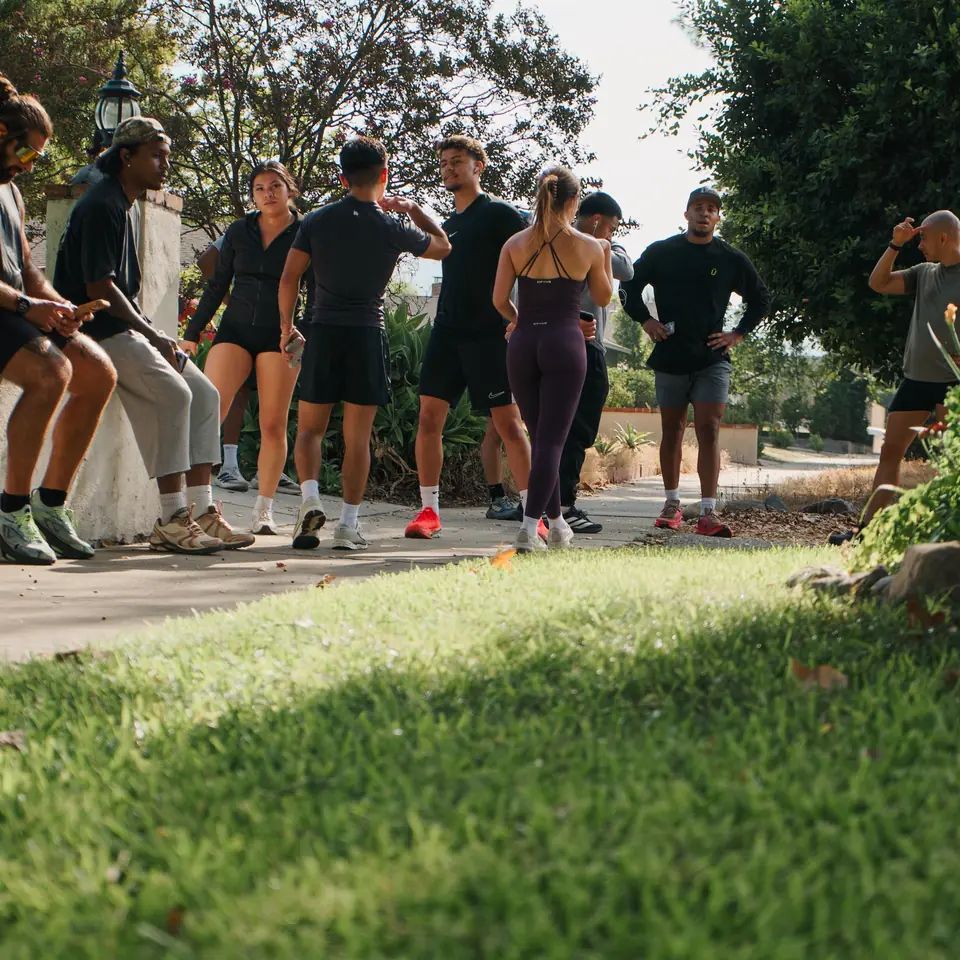 Runners stretching and chatting on a shady path before heading out