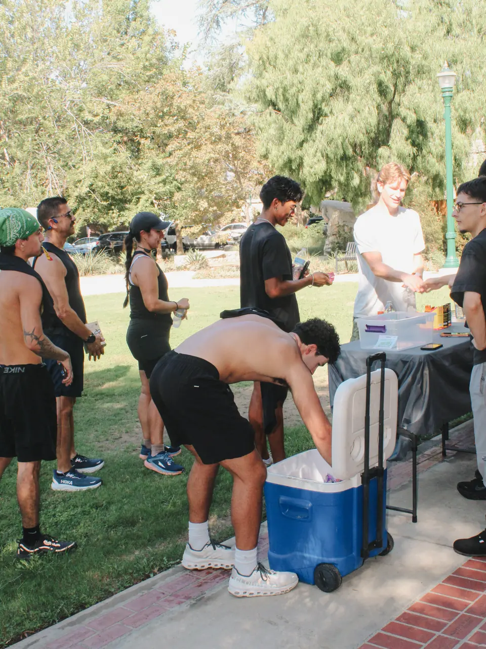 Runners grabbing cold drinks from a cooler on the grass at Shelton Park after the run