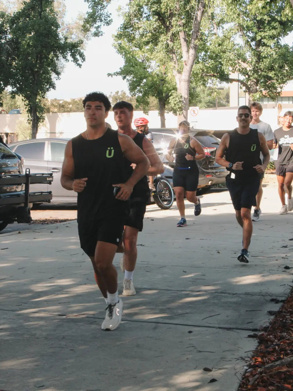 Runners in matching black tanks with the green Ü logo holding a steady pace