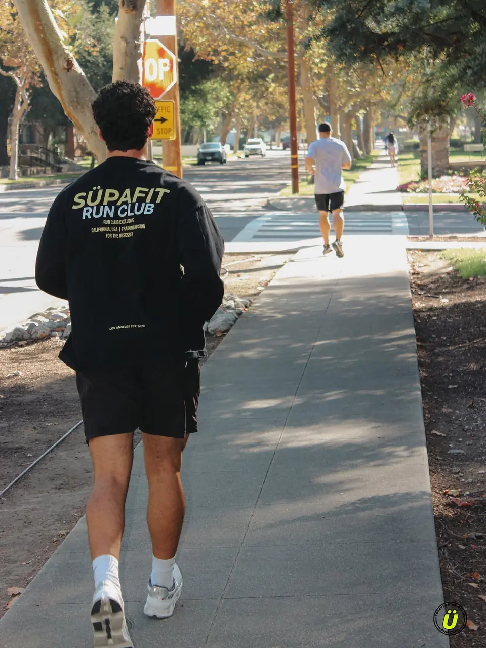 Runner in a SÜPAFIT Run Club long sleeve on a shady neighborhood sidewalk