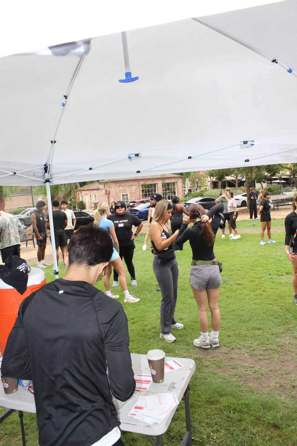 Runners tying back their hair and getting ready under the check in tent