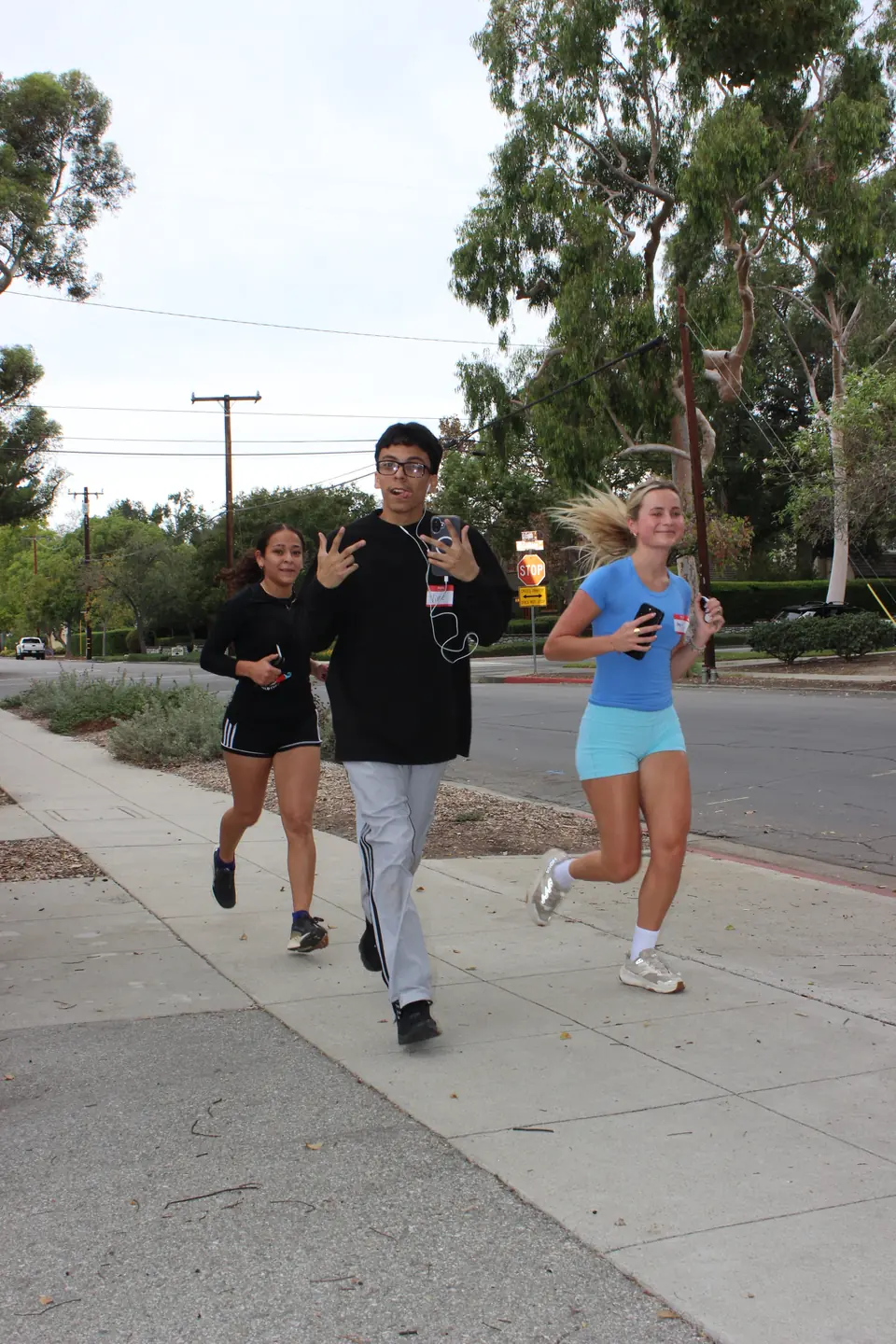 Three runners with name tags jogging along a quiet residential street